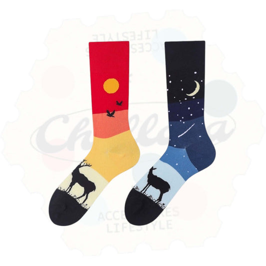 Chaussettes fantaisie dépareillées avec un cerf au coucher de soleil sur fond rouge et jaune, et un autre cerf sous un ciel nocturne étoilé avec lune et étoiles – motif nature contrasté jour/nuit.