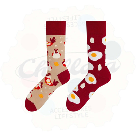 Chaussettes fantaisie dépareillées motif poules et œufs : une chaussette beige avec des poules, poussins et empreintes, l’autre rouge foncé avec des œufs au plat sur toute la surface.