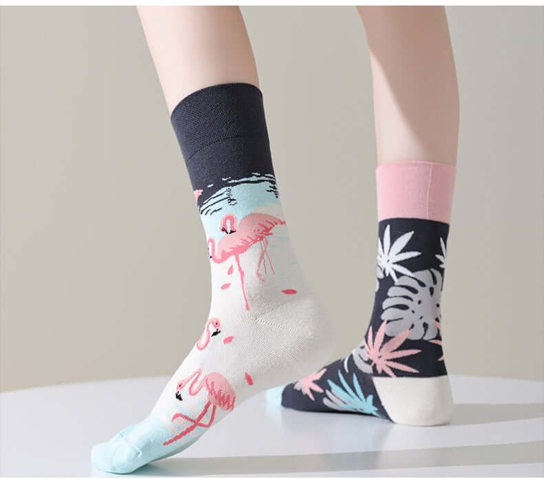 Chaussettes fantaisie dépareillées avec un motif flamant rose sur fond clair et un motif feuillage tropical coloré sur fond noir